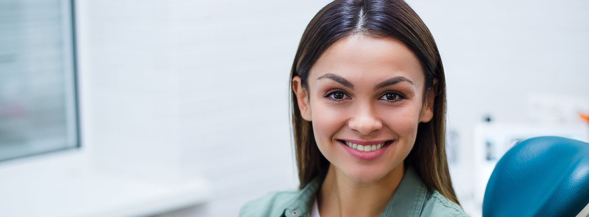 A smiling woman in a professional environment, likely a dental or medical office.