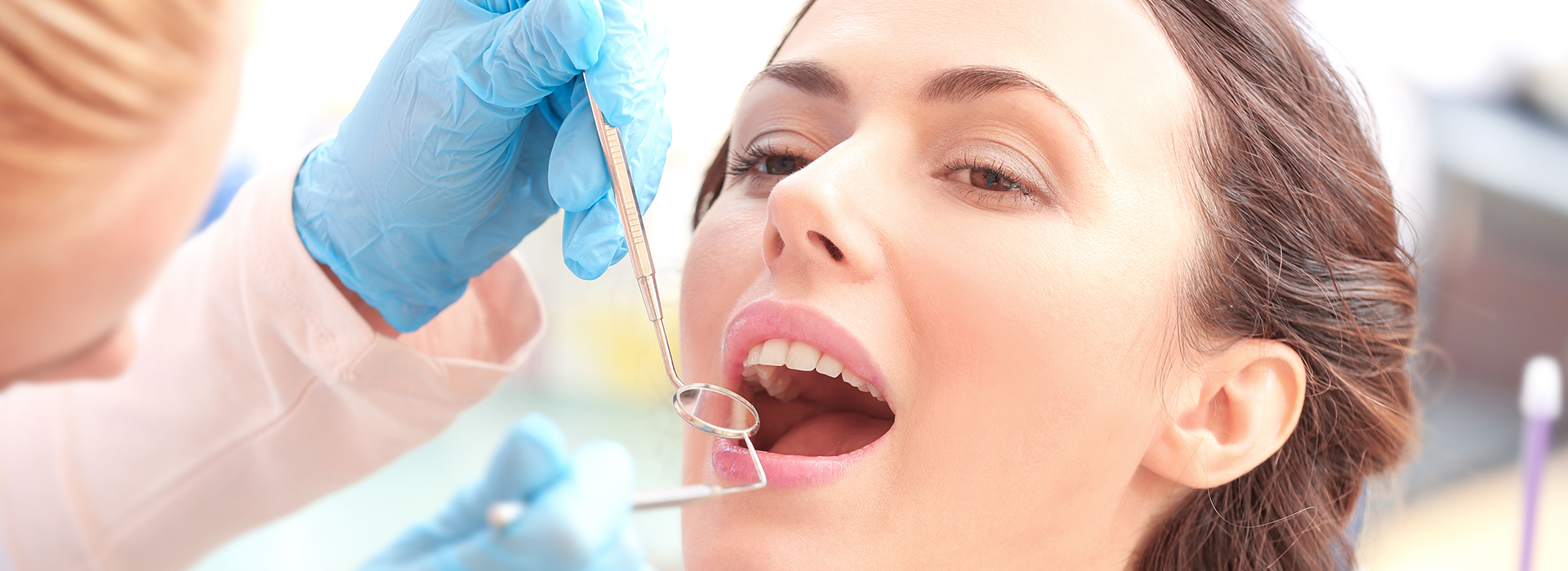 A woman receiving dental treatment, with a dentist working on her teeth and gums.