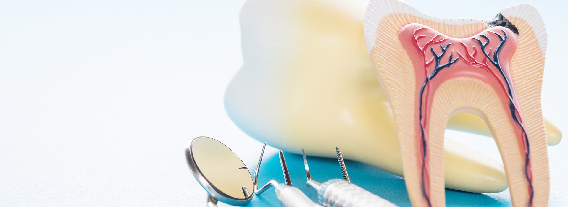 The image shows a close-up of dental tools and models, including a toothbrush, toothpaste, floss, and a dental mirror, set against a background with a blue color scheme.