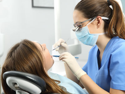 A dental hygienist performing a cleaning procedure on a patient in a professional dental office setting.