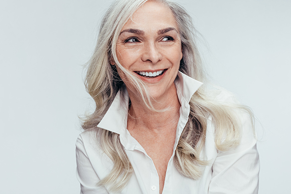 A woman with short hair, smiling and looking to the side, against a white background.